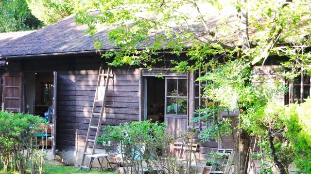 緑に囲まれた地方の古い木造住宅。都会で暮らす子どもが相続する実家のイメージ。